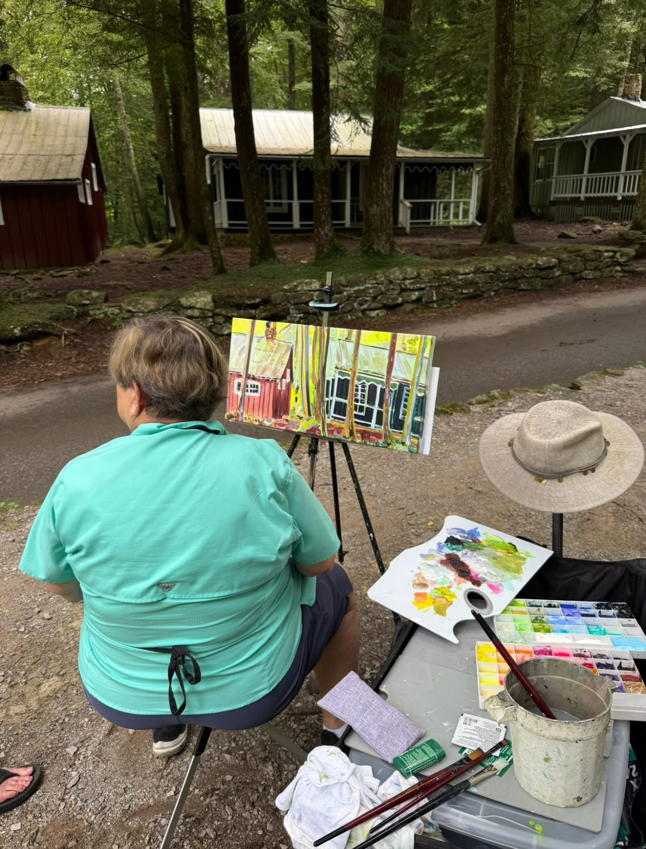Artist Charlotte Rollman, outside painting in acrylic 12x24 inches of Daisy Town in the Great Smoky Mountans.