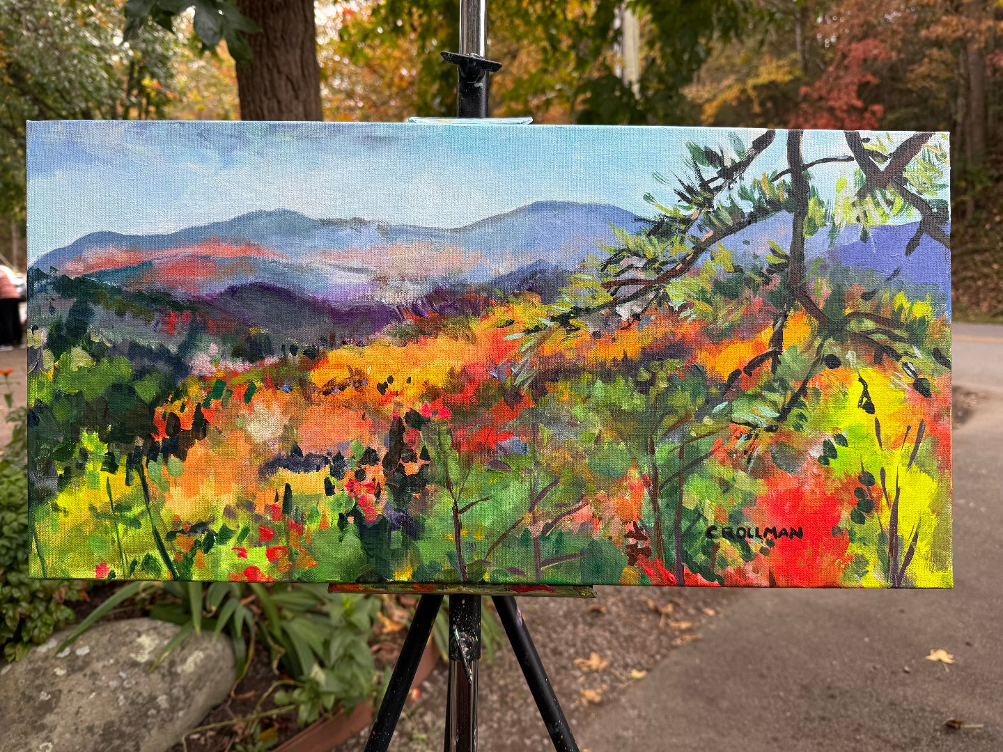 Colorful landscape painting on an easel outdoors. Painting by Charlotte Rollman - Adkins Rollman Gallery.